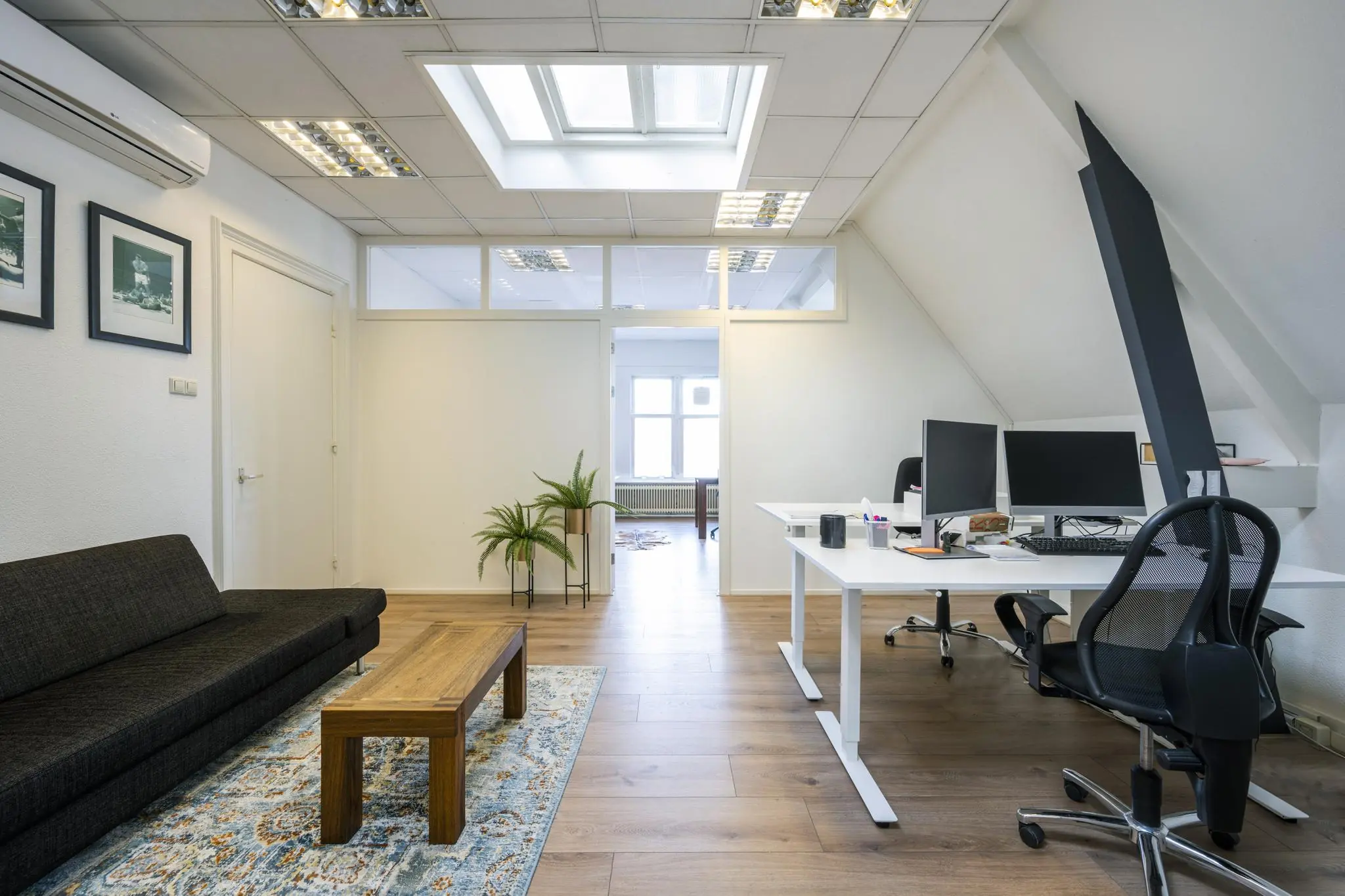 Modern ingerichte kantoorruimte aan de Van Eedenstraat met bureau, zithoek en dakraam.